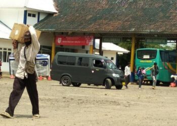 TERMINAL BUS: Penumpang yang turun dari bus di Terminal Labuan, sedang berjalan kaki sambi membawa barang bawaannya untuk kembali bergegas ke kediamannya, Senin (3/8). (NIPAL/SATELIT NEWS)