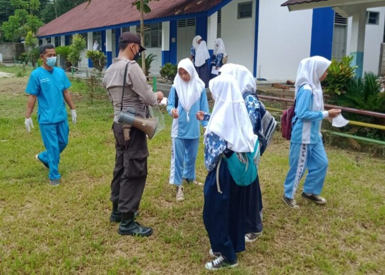 BAGIKAN MASKER–Jajaran personel Polsek Jiput, membagikan masker sambil mengimbau disiplin Prokes, di lapangan SMP Negeri 2 Jiput, Kamis (21/10/2021). (ISTIMEWA)
