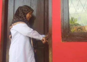 KEBOBOLAN–Kepala SD Negeri 4 Pandeglang, Nani Sri Hernani, sedang menunjukkan kondisi pintu kantornya yang berhasil dibobol maling, Rabu (18/5/2022). (ISTIMEWA)