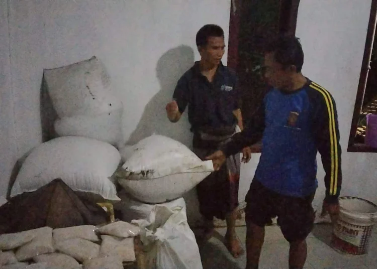 Seorang warga dibantu anggota Tagana, mengamankan dan menyelamatkan barang-barang, agar tidak terendam banjir, Kamis (12/5/2022) malam. (ISTIMEWA)