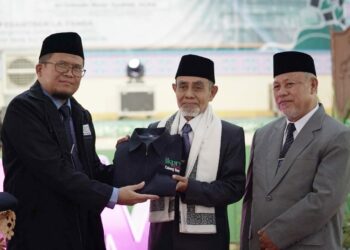 Ketua IKPM PMG Cabang Banten, K.H. Sholeh Rosyad (kiri), memberikan jaket "kebesaran" kepada Pimpinan PMG K.H. Hasan Abdullah Sahal (tengah). (ISTIMEWA)